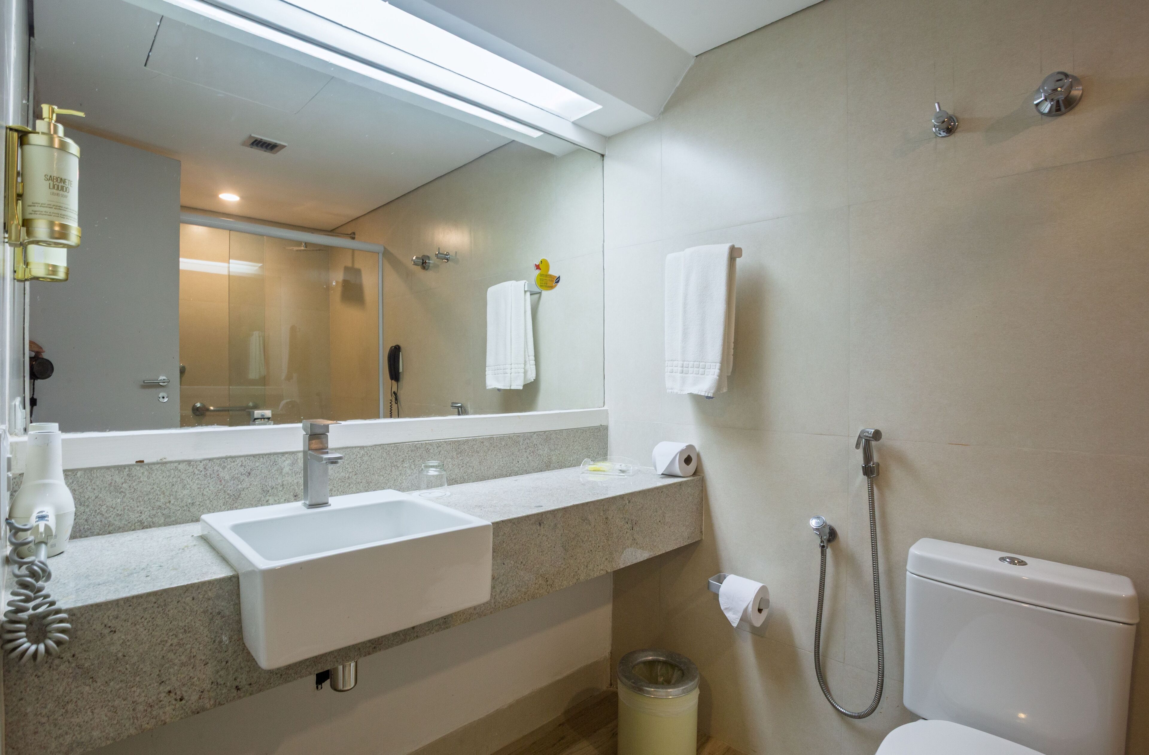 Un baño moderno con lavamanos, espejo e inodoro.