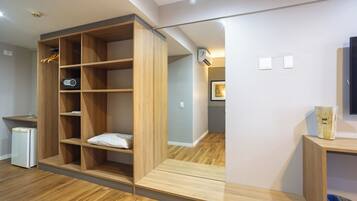 Una habitación moderna con estanterías empotradas de madera, un pequeño cubo de basura y un refrigerador.