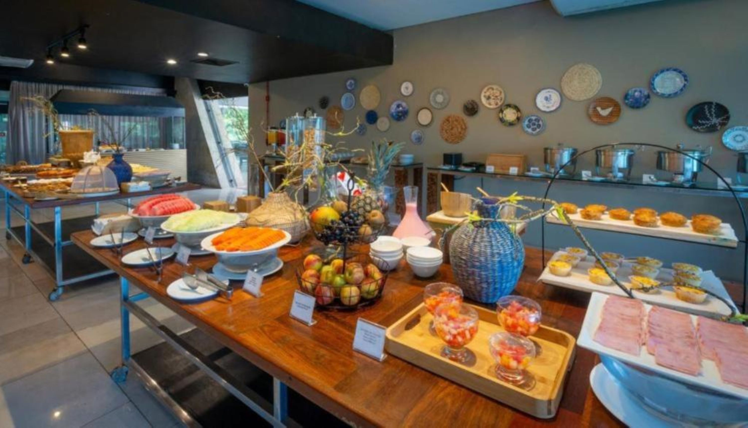 Un buffet proposant une variété de plats et un mur décoratif orné d’assiettes.