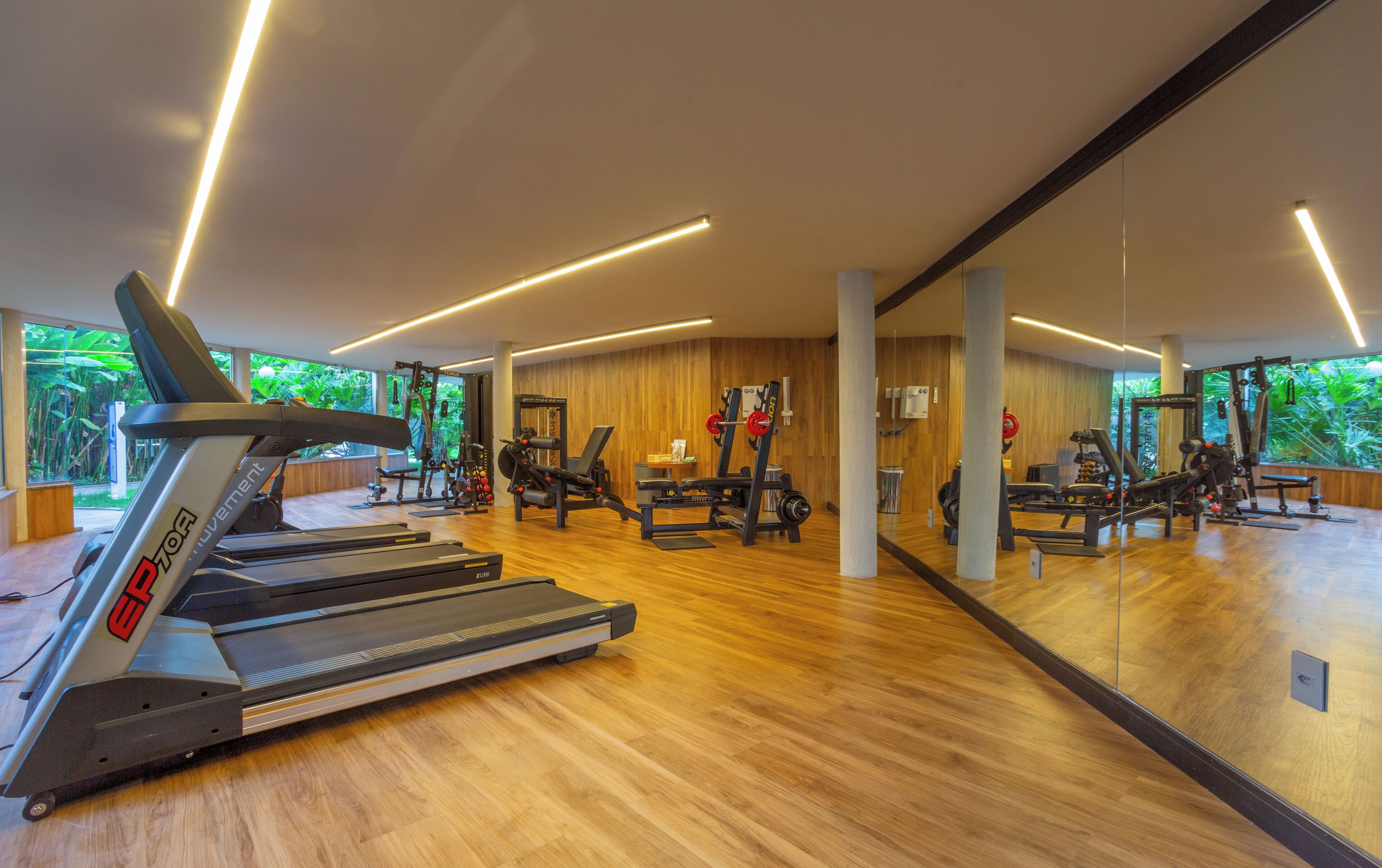 Et moderne fitnesscenter med løbebånd, træningsmaskiner og en stor spejlvæg.