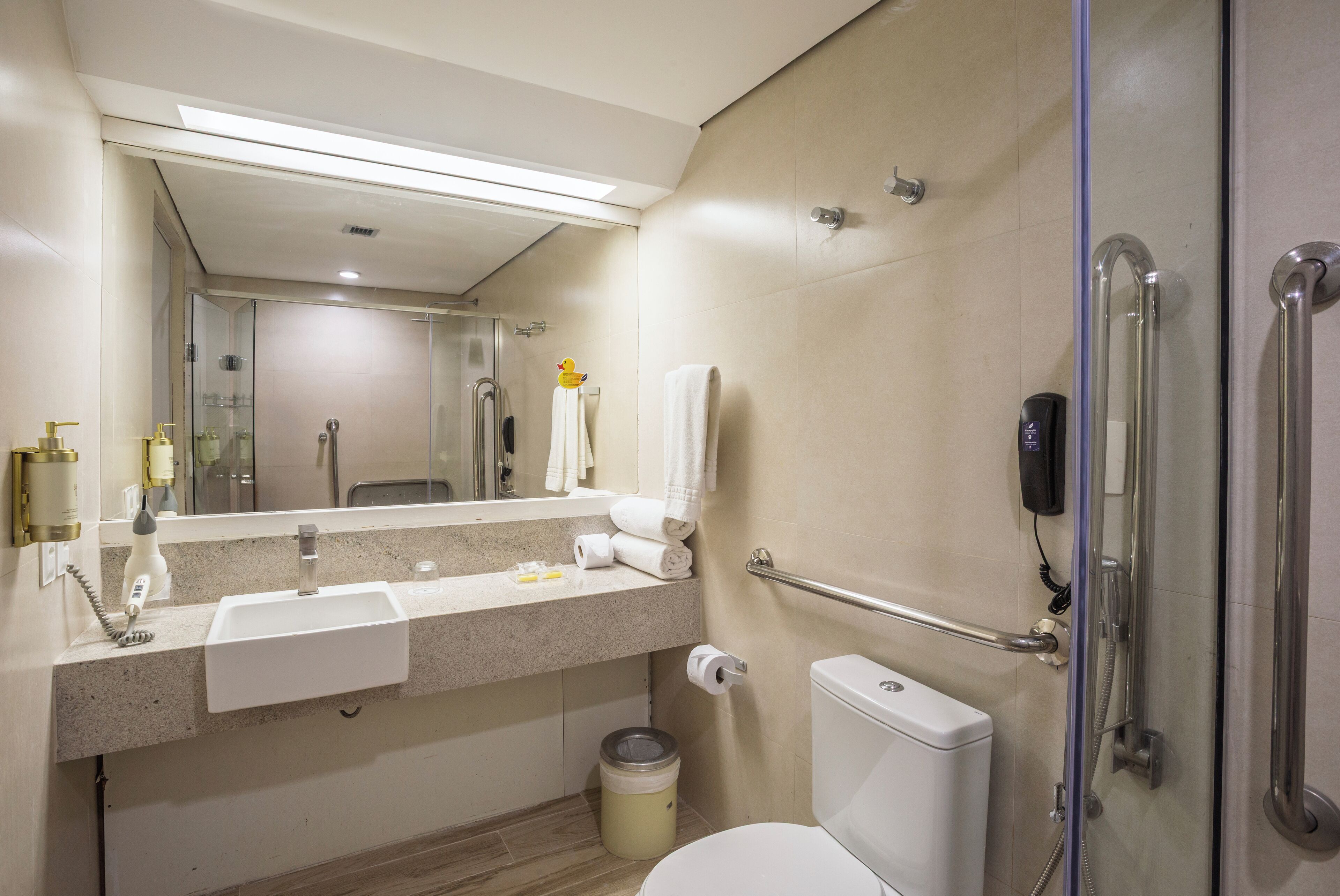 Un baño moderno con lavamanos, espejo, inodoro y ducha.