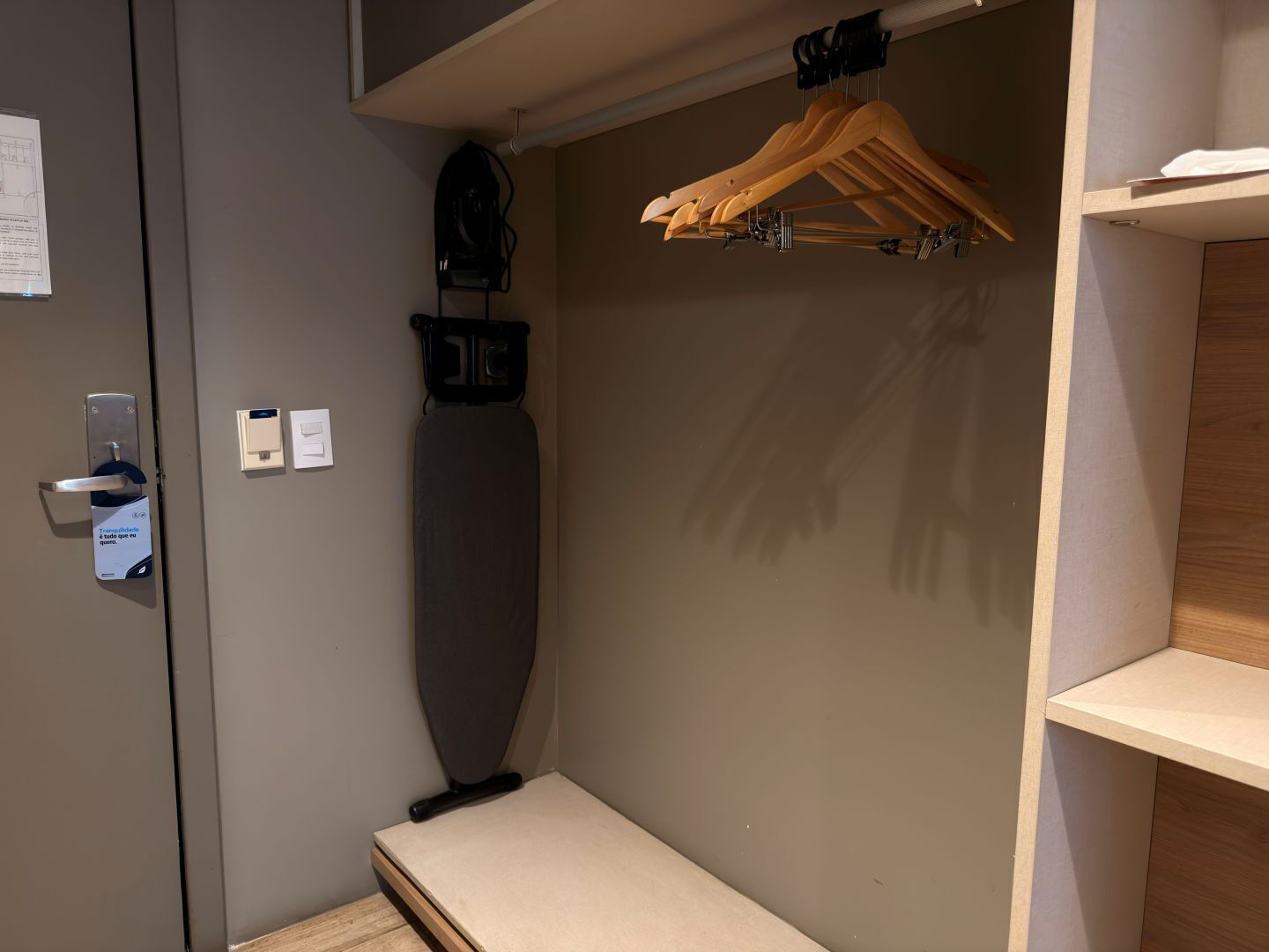A compact room with a built-in bench, a wooden hanger rack, and a small shelf.
