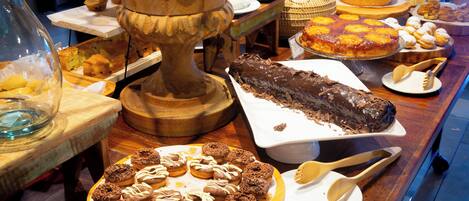 Un bufé con diversos postres, entre ellos pasteles, repostería y un pastel de chocolate.