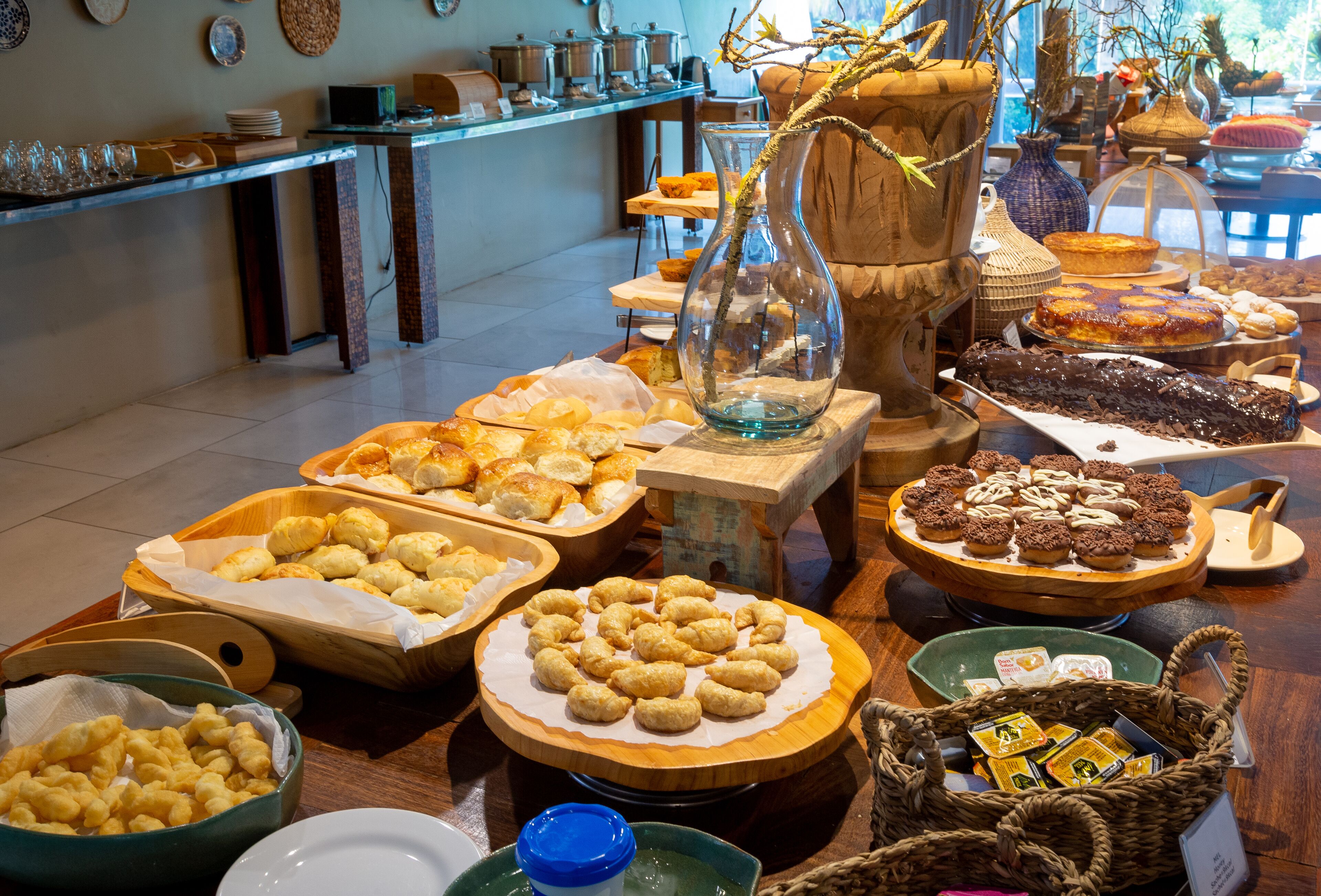 A buffet table with various pastries and desserts, a vase with branches, and a coffee station.