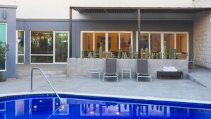 A modern outdoor pool area with a pool, lounge chairs, and a cactus garden. - Fairfield by Marriott Los Cabos (Cabo San Lucas)