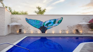 Una piscina al aire libre, sombrillas, tumbonas