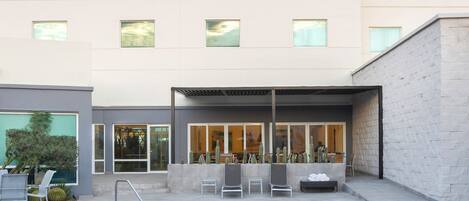 A modern hotel with a pool area, outdoor seating, and a view of the building's facade.
