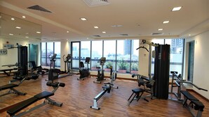Een sportschool met diverse fitnessapparaten, grote ramen en uitzicht op de stad.