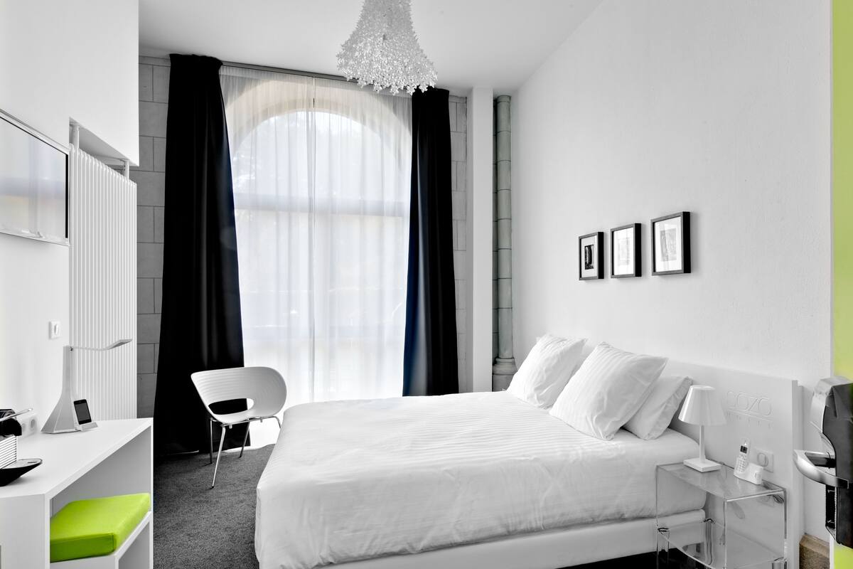 Una habitación de hotel moderna con una cama grande, un escritorio con una silla, una lámpara de escritorio y un teléfono.
