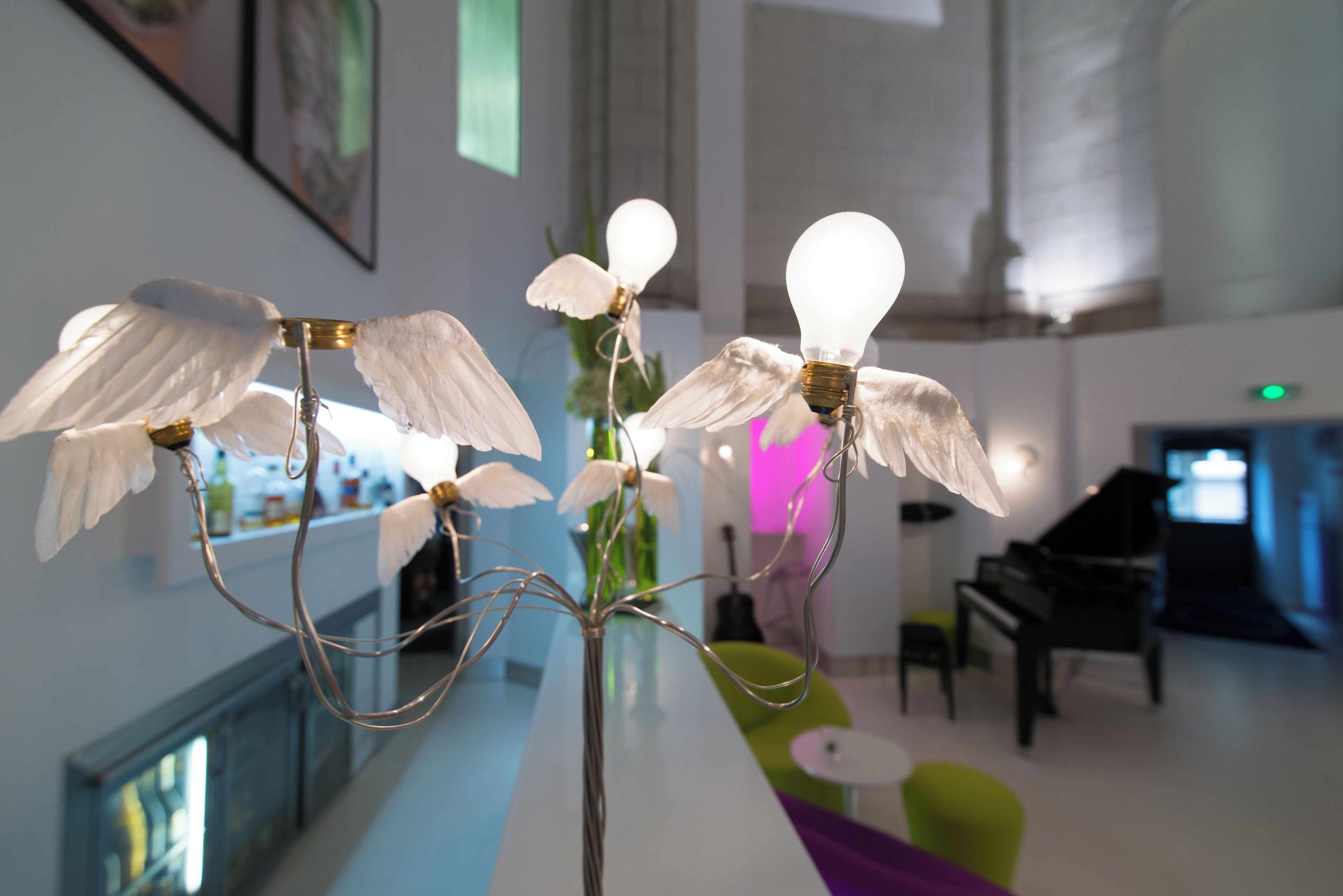 A modern interior with a long table displaying decorative light fixtures shaped like birds.