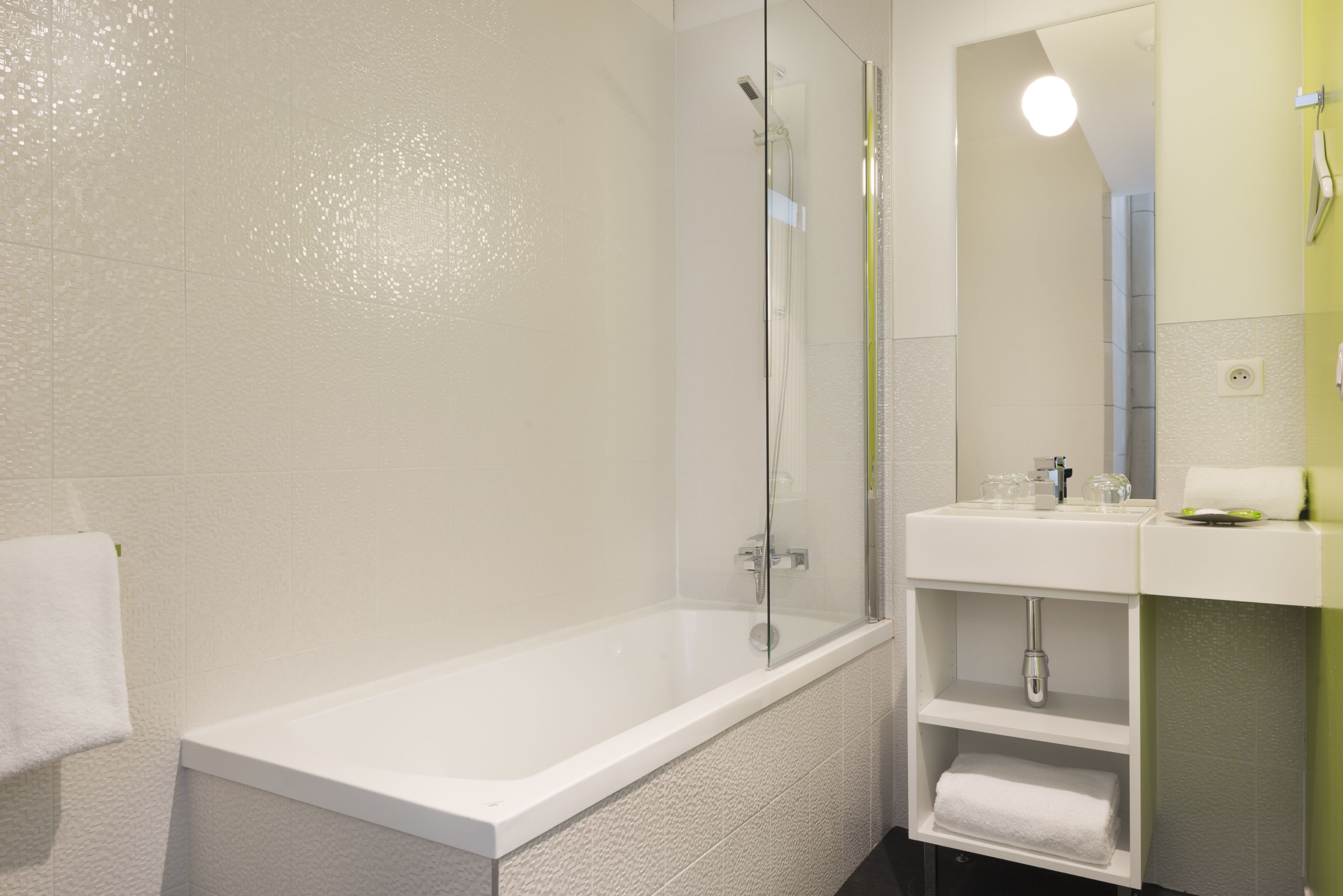 Un baño moderno con bañera, ducha con mampara de vidrio y lavamanos con espejo.