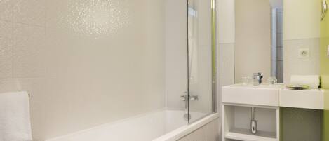 Un baño moderno con bañera, ducha con mampara de vidrio y lavamanos con espejo.