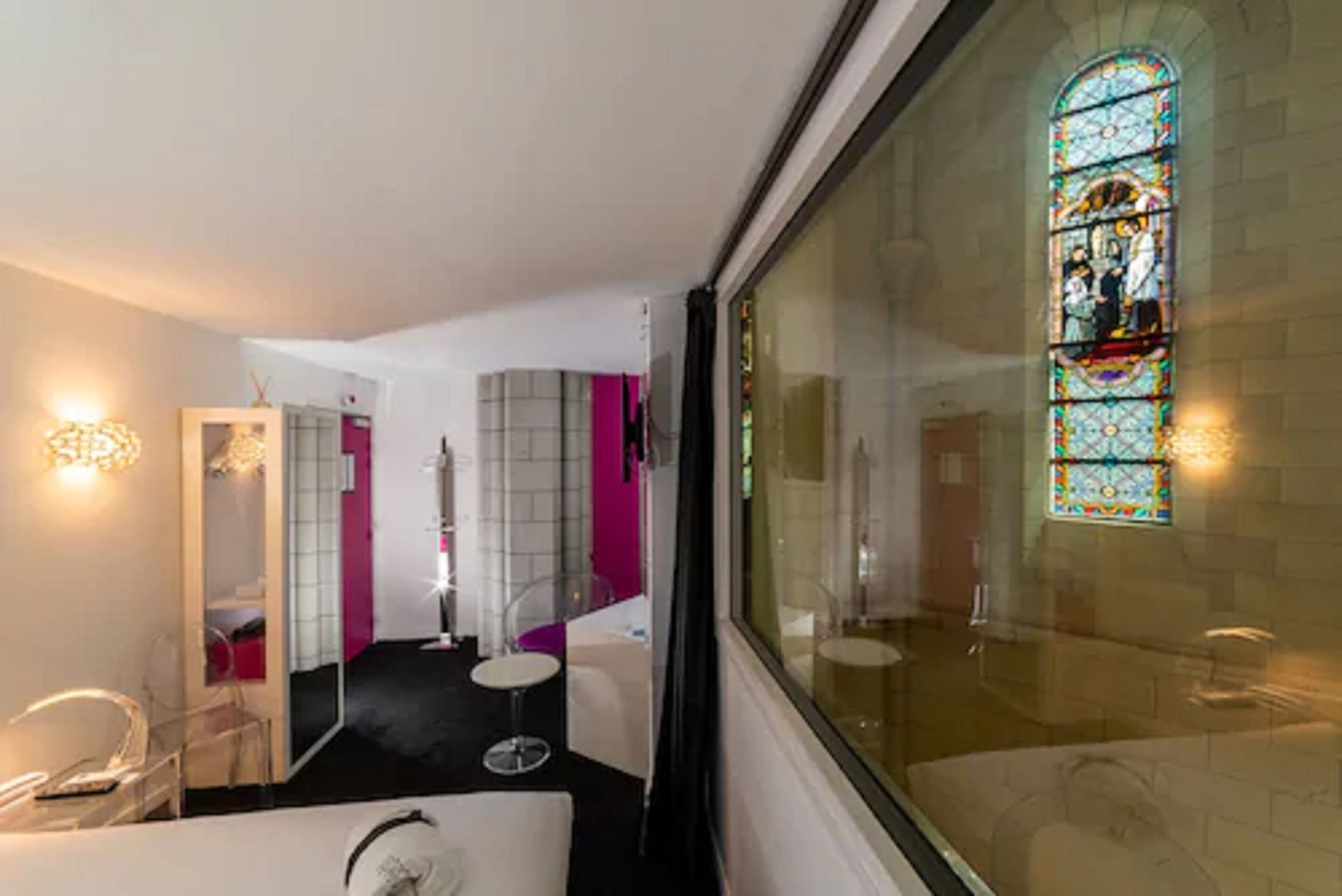 Un baño de hotel con un amplio ventanal de vitral, un espejo y un lavabo.