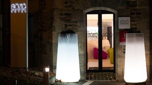 Ingresso di un hotel con facciata in pietra, insegna al neon e interno moderno visibile attraverso la porta.