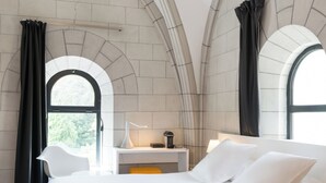 Una camera da letto moderna con un letto grande, una scrivania e due finestre con tende.