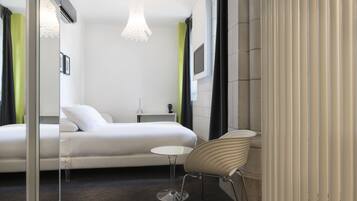 Una habitación de hotel moderna con una cama, una mesita, una silla y un televisor.
