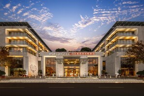 Un hôtel moderne doté d’une entrée imposante, de grandes fenêtres et offrant une vue sur un ciel dégagé.