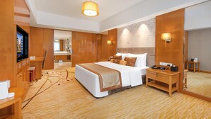 A hotel room with a large bed, bedside table, mirror, and a television. - WorldHotel Grand Juna Wuxi (Wuxi)