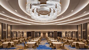 A large conference room with round tables and chairs, a patterned carpet, and a modern chandelier. - Mercure Padang (Padang)
