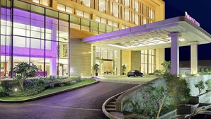 A hotel entrance with a covered driveway, glass facade, and a sign that reads "Marriott". - Mercure Padang (Padang)