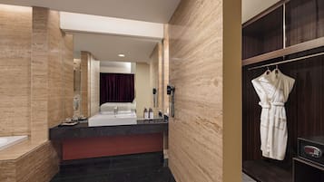 Un baño moderno con un espejo grande, un lavabo, tocador y una bata colgada en un perchero, además de una zona de ducha.