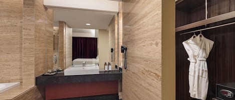 Un baño moderno con un espejo grande, un lavabo, tocador y una bata colgada en un perchero, además de una zona de ducha.