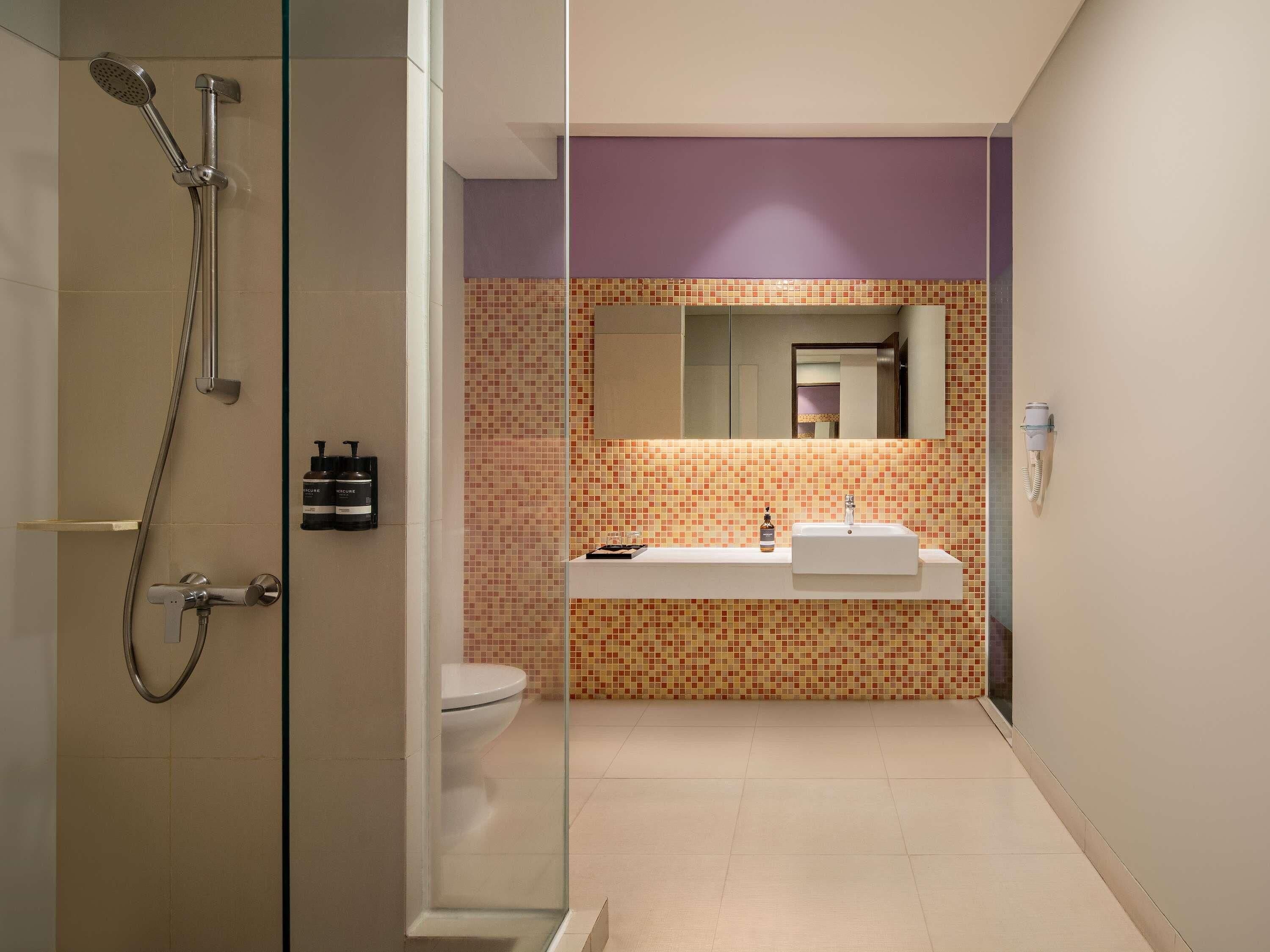 A modern bathroom with a glass-enclosed shower, a white sink, and a tiled backsplash.