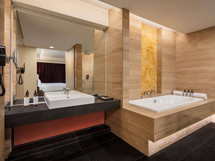 Un baño moderno con dos lavamanos, una bañera grande y un espejo.