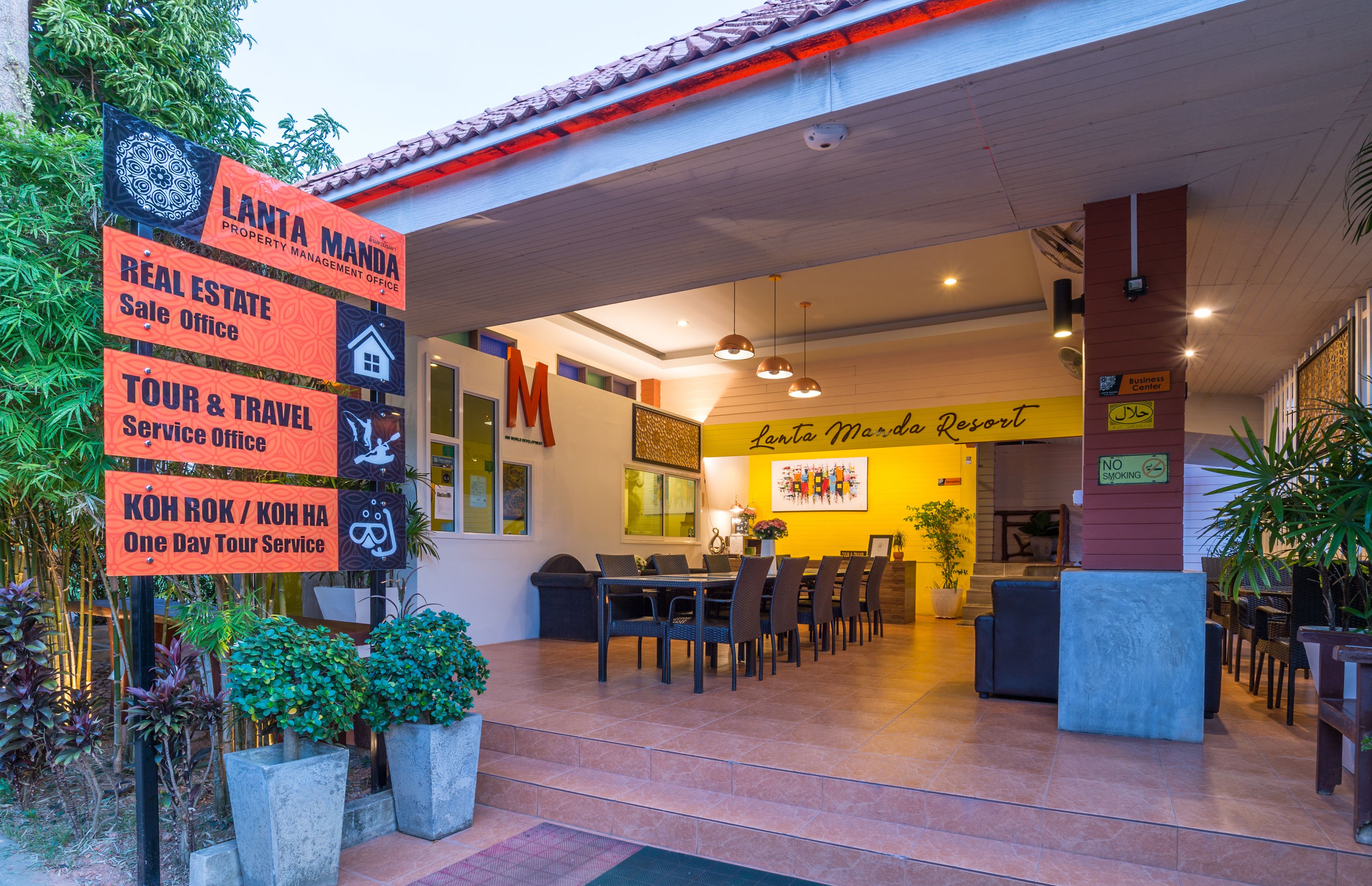 A hotel lobby with a reception desk, seating area, and signs for services like real estate, tour & travel, and a one-day tour service.