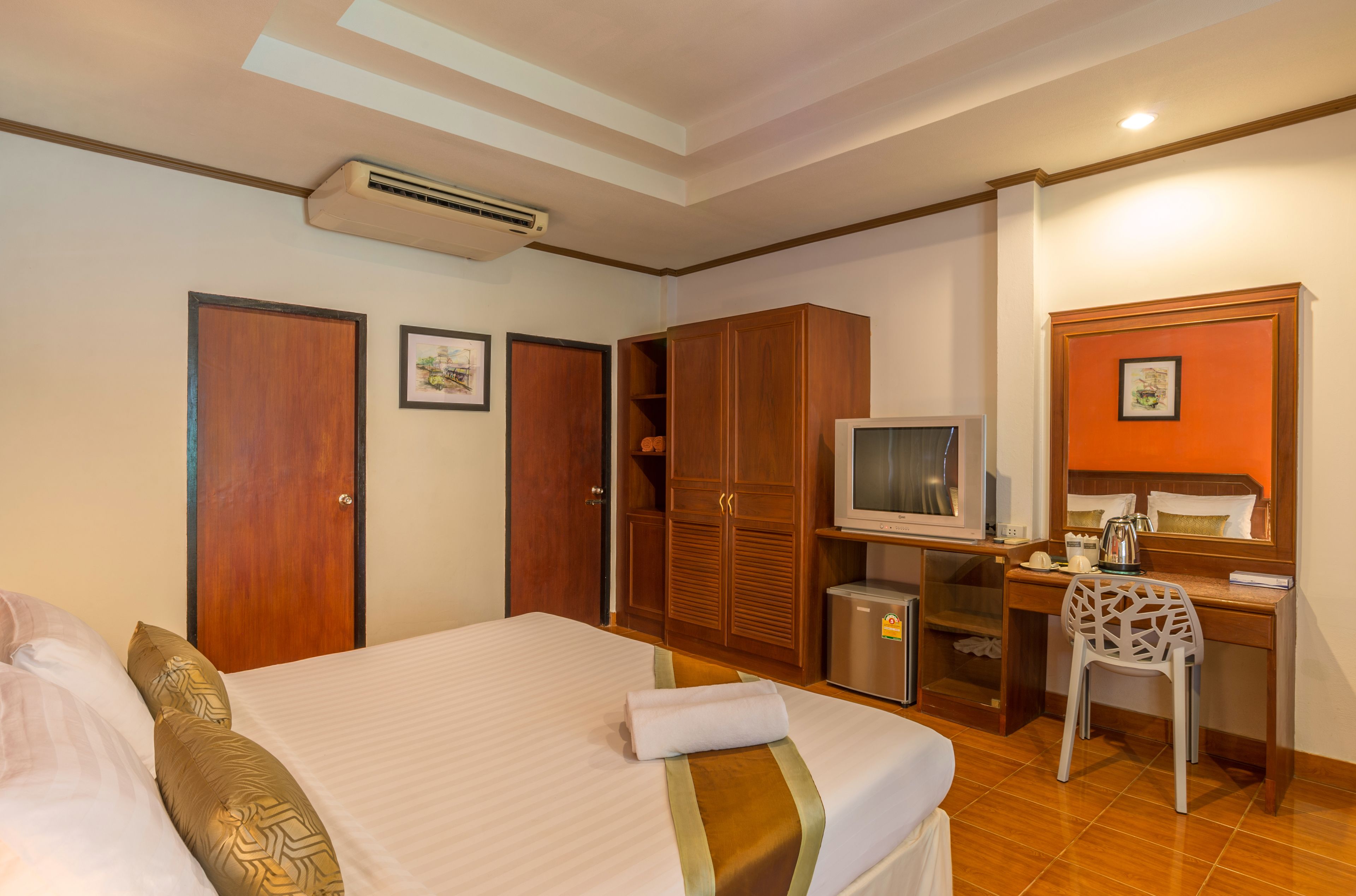Een hotelkamer met een bed, een bureau, een televisie en een kledingkast.