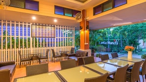 Restaurante com mesas ao ar livre, cerca branca e placa com o nome 'Lanta Manda'.