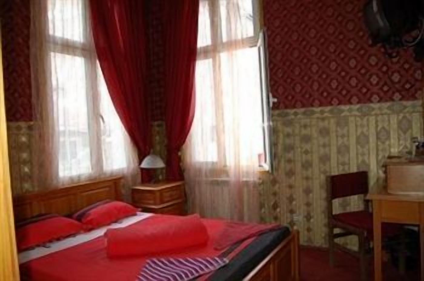 Une chambre à coucher avec un lit, une chaise, un bureau et une fenêtre avec des rideaux.