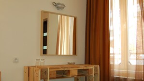 Une pièce avec un bureau en bois, un miroir et une fenêtre avec des rideaux.