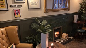 Et hyggeligt opholdsområde med en læderlænestol, et lille rundt bord med et lys og et spejl på væggen.