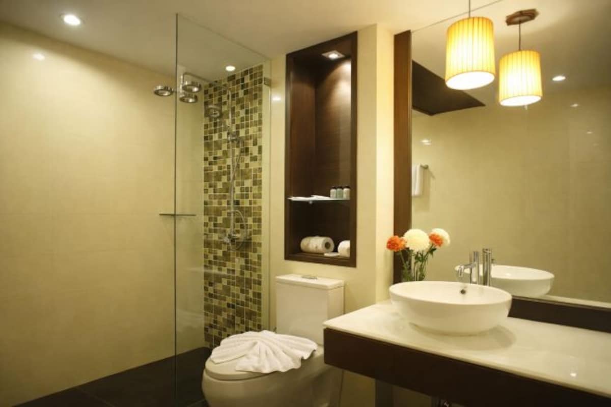 Un baño moderno con cabina de ducha de vidrio, tocador con lavabo y espejo.
