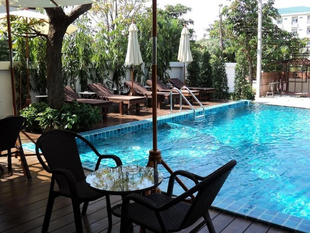 A swimming pool with lounge chairs and umbrellas, surrounded by greenery.