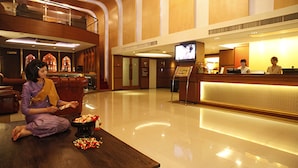 Un vestíbulo de hotel con mostrador de recepción, zona de estar y una pantalla de televisión.