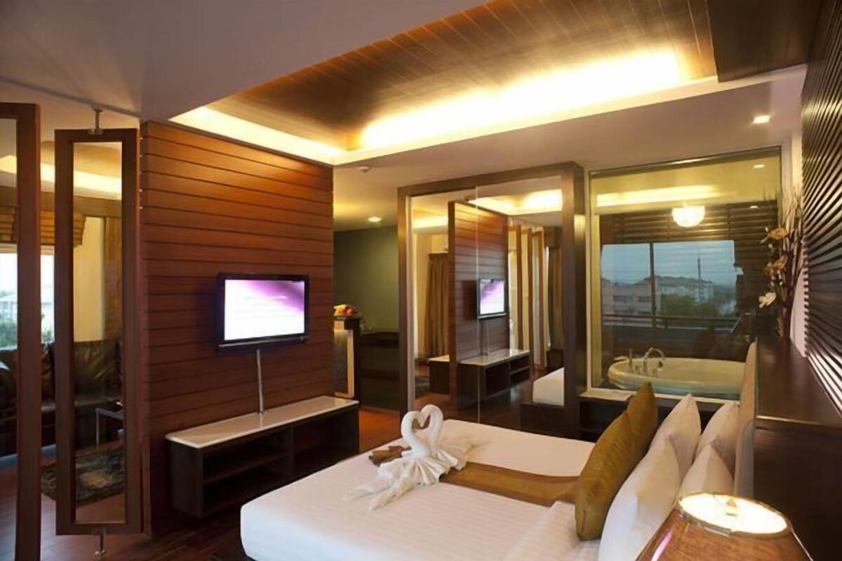 A modern hotel room with a bed, a TV, a mirror, and a view of the city.