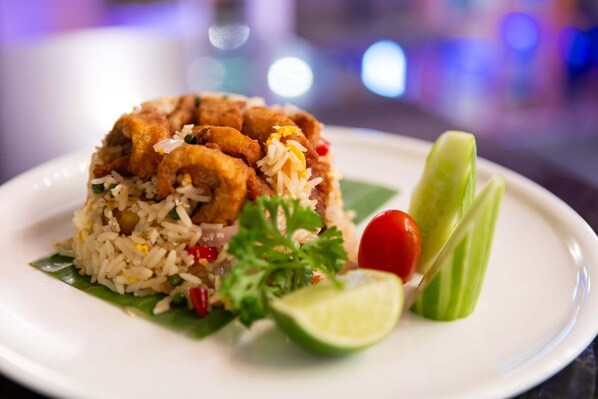 A plate of fried rice with vegetables and a lime wedge. - Suvarnabhumi Suite (Bangkok)