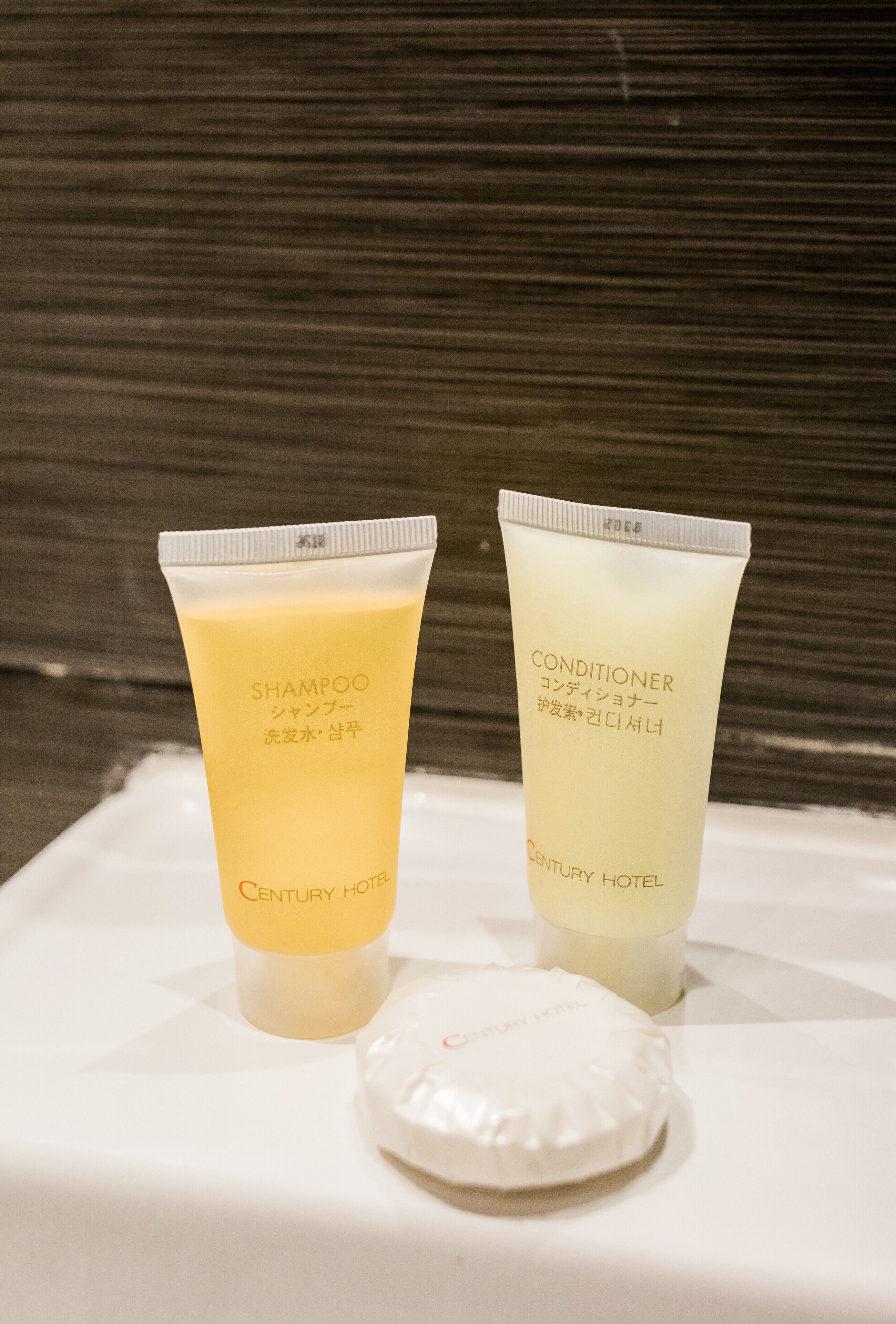 Two tubes of shampoo and conditioner from Century Hotel on a white surface.