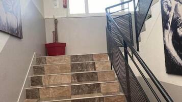 A staircase with alternating dark and light tiles leading to an upper floor.