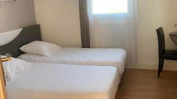Quarto de hotel com duas camas, uma escrivaninha e uma cadeira.