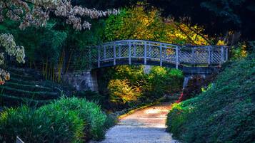 A stone bridge over a gravel path surrounded by lush greenery and trees.