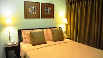 A hotel room with a bed, two bedside lamps, a nightstand, and two framed pictures on the wall.