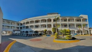 A multi-story hotel with a central courtyard, featuring a circular seating area and small trees. - Hotel Pueblito Inn (Playas de Rosarito)