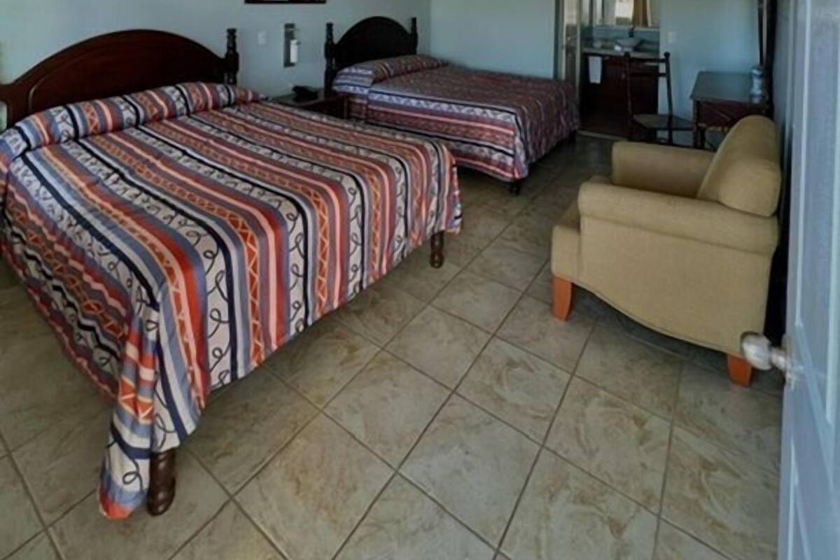 A hotel room with two beds, a sofa, a desk, and a chair.