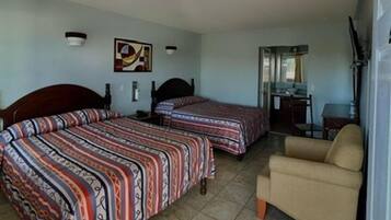 A hotel room with two beds, a sofa, a desk, and a chair.