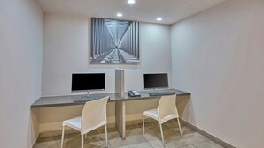 A modern office space with two desks, two chairs, two monitors, a telephone, and a large abstract painting on the wall. - City Express Junior by Marriott Guadalajara Periférico Sur (Tlaquepaque)