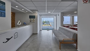 A reception area with a bench, a reception desk, and a view of the outside. - City Express Junior by Marriott Guadalajara Periférico Sur (Tlaquepaque)