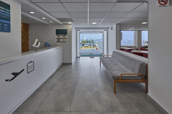 A reception area with a bench, a reception desk, and a view of the outside.